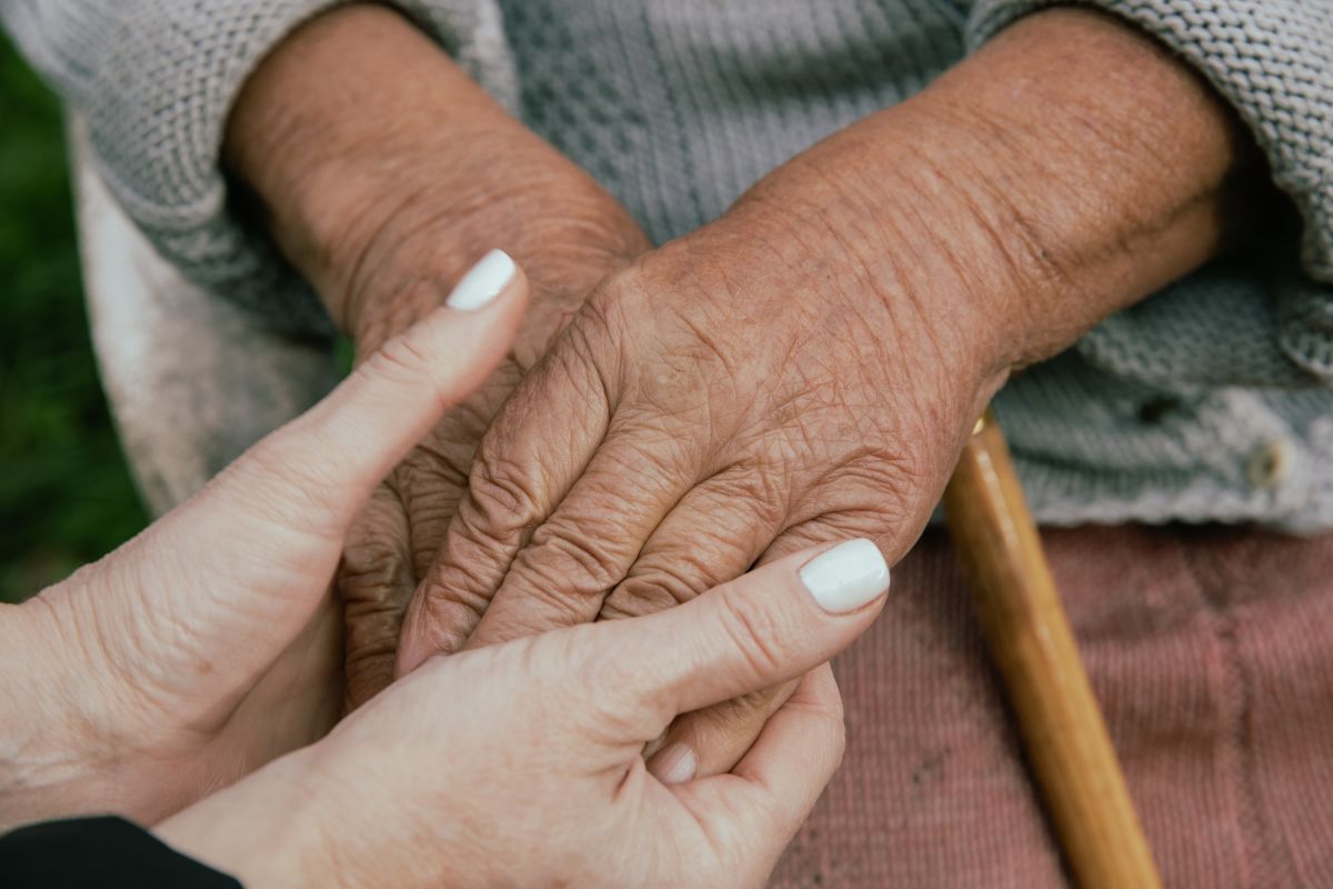 cuidadora a segurar as mãos de uma idosa